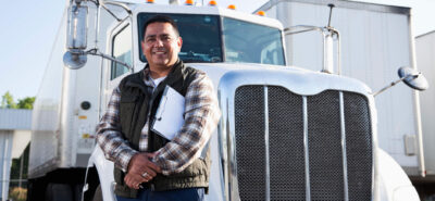 a happy man driver in front of his truck